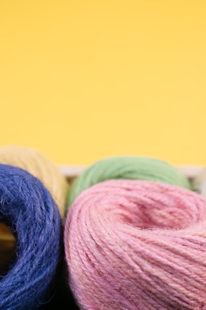 A vertical shot of colorful yarns on a box isolated on yellow background