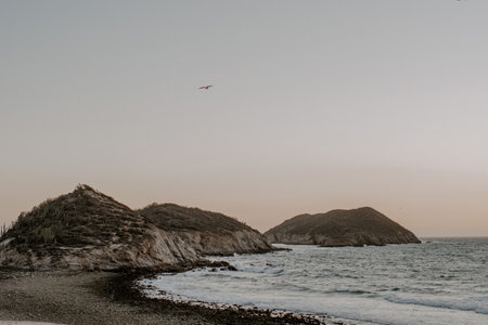 A closeup shot of a coast during the evening with beautiful small hills and sea waves