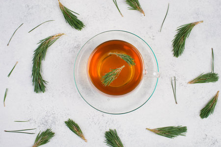 Pine needle tea in a cup on a white textured background, empty copy space for text, hot drink, fresh twigsの写真素材
