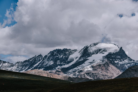 A snow-capped mountain range under a cloudy sky at the Gran Paradiso National Park in the Italian...