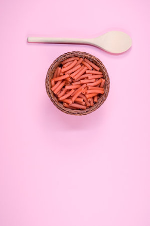 A vertical shot of macaroni with a spoon on a light pink backgroundの写真素材