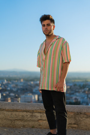 A handsome Caucasian guy wearing a striped shirt posing in the streetの写真素材