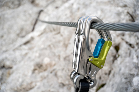 Via ferrata set with coloured carabiners hangs on a wire rope on a rocky mountain. close up