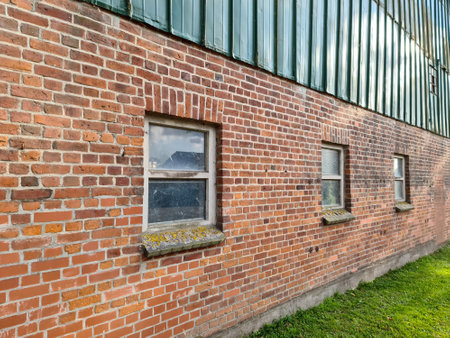 A brick wall with windows of a barn on a farmの写真素材