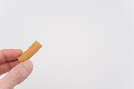 A high angle shot of a person holding an uncooked pasta over a white surfaceの写真素材