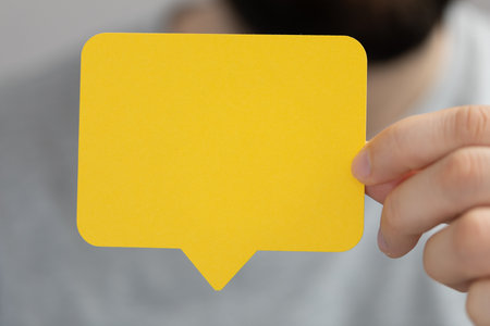 A male's hands holding a communication paper speak bubbleの写真素材