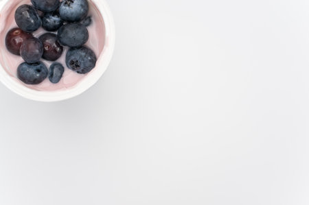 A high angle shot of a cup of yogurt with fresh berries on a white surfaceの写真素材
