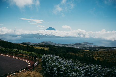 A view of scenic diverse landscapes and the Pico island in the dense clouds in the background