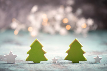 A closeup shot of Christmas ornaments, small green trees, and white stars on a blue boardの写真素材