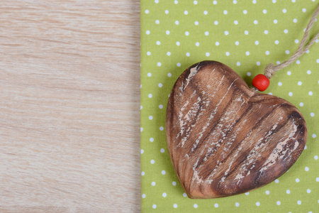 A heart-shaped necklace on a green paper on a brown table surfaceの写真素材