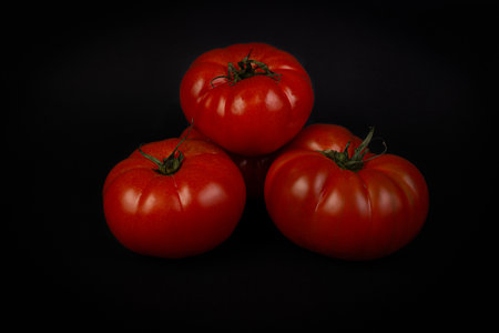 A closeup shot of red juicy tomatoes on a black backgroundの写真素材