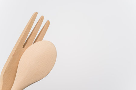 A high angle shot of a wooden spoon and fork on a white surface
