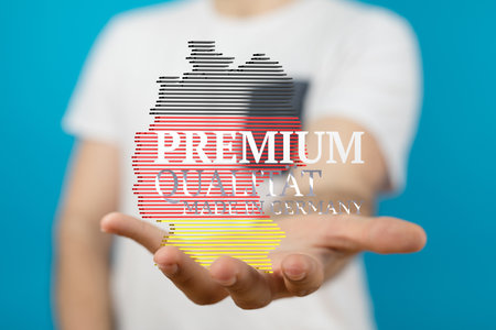 A closeup of a Caucasian man holding a 2D illustration of the map of Germany with its flag in his handの写真素材