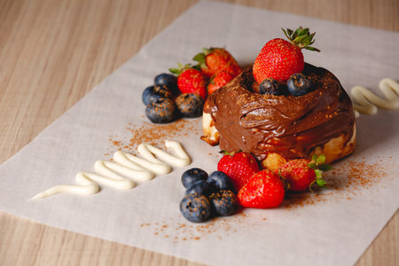 A closeup shot of a delicious Cinnabon on the table with cream and jam on top with berries