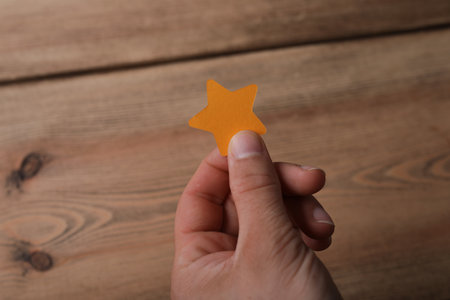A man holding a minimal star paper cut out on a wooden surface