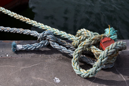 A rope with many knots is wrapped around a bollard on the pier of Ruegen