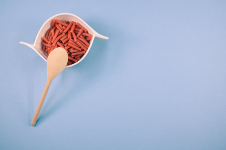 A bowl of macaroni pasta with a wooden spoon isolated on a blue background with free space for textの写真素材