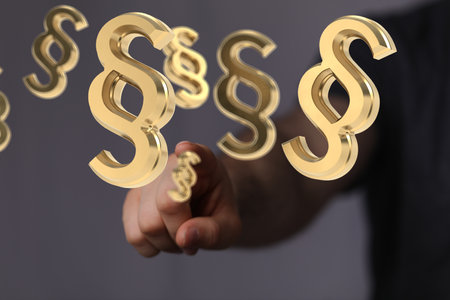 A hand touching floating 3D paragraph law and justice signsの写真素材