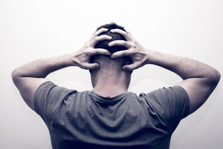 A nervous man hands in the head on a gray backgroundの写真素材