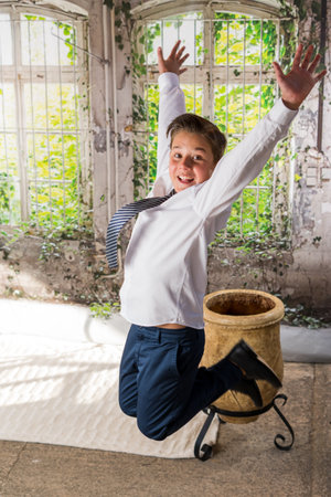 A vertical shot of an adorable male child in a formal outfit posing while jumpingの写真素材