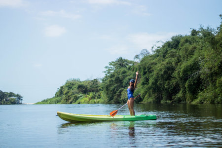 A scenic view of a Hispanic woman kayaking on a lake