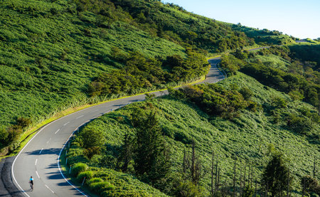 A winding road in a green mountainous area in the morningの写真素材