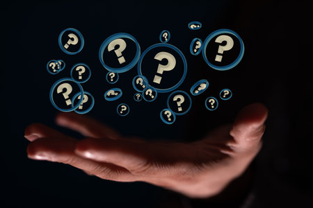 A male's hand holding illustrated question marks in blue circles on a black backgroundの写真素材