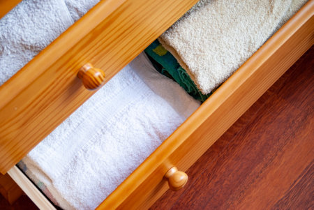 A high-angle shot of open wooden brown drawers with white clean towels insideの写真素材