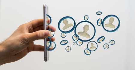A person's hand holding a phone with 3D rendered people silhouettes in the network teamの写真素材