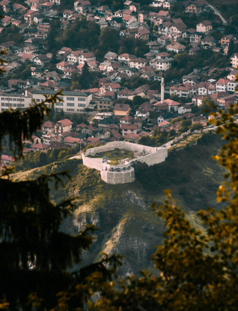 A vertical shot of a beautiful fortress and a city from viewpoint through the treesの写真素材