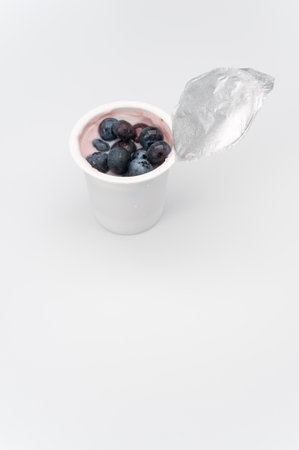 A vertical shot of a cup of yogurt with fresh berries on a white surfaceの写真素材