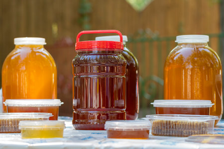 On the table are glass jars and plastic containers filled with Bashkir bee honey and ready to be...