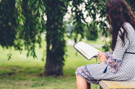 A young Caucasian man reading the Bible while sitting on a benchの写真素材