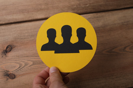 A hand holding a yellow circle with person iconsの写真素材