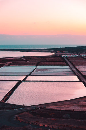 A vertical shot of natural salt evaporation ponds at scenic sunsetの写真素材