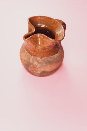 A vertical shot of a handmade pitcher on a pink surfaceの写真素材