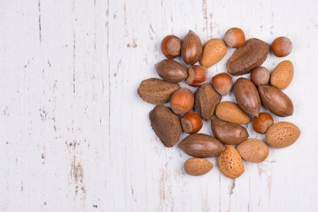Mix of nuts on a textured background, empty copy space for text, hazelnuts, walnuts, peanuts