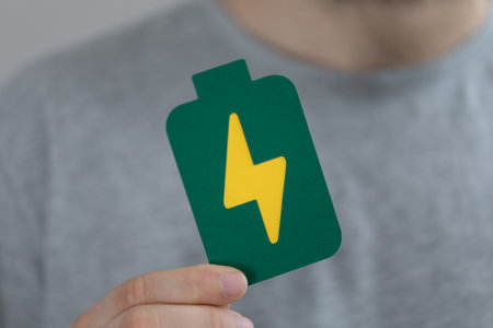 A male's hand holding a paper battery - electric eco-friendly battery iconの写真素材