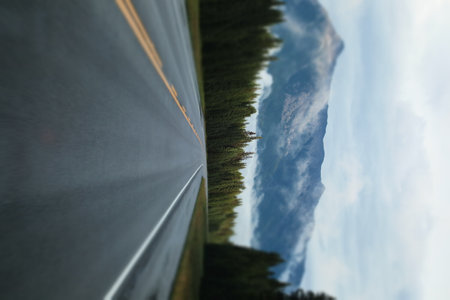 A smooth highway passing through a scenic forest; picturesque mountains in fog in the backgroundの写真素材