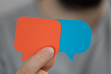 A male's hand holding paper speech bubblesの写真素材
