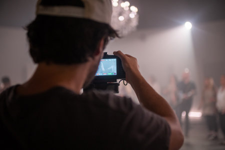 A rear view of cameraman holding a camera on a studioの写真素材