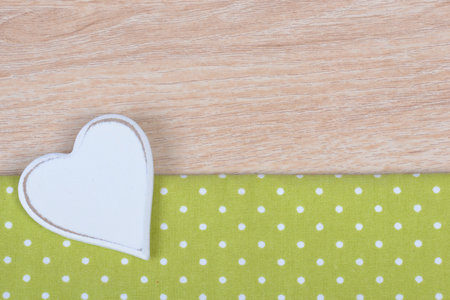 A heart-shaped decor on a green dotted paper on the table surfaceの写真素材
