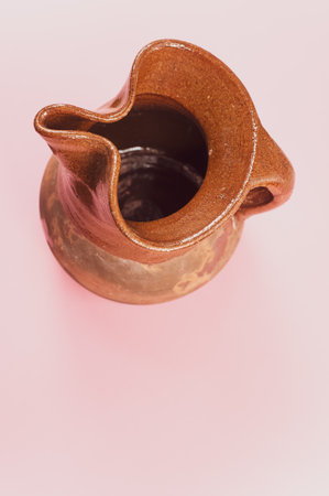 A vertical shot of a handmade pitcher on a pink surfaceの写真素材