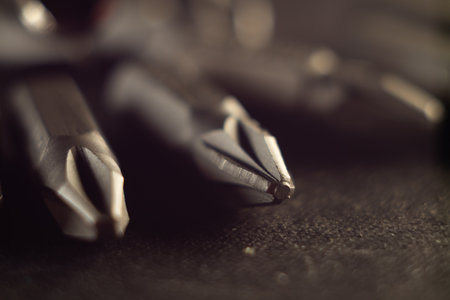 A selective focus shot of screwdriver bits on a dark surfaceの写真素材