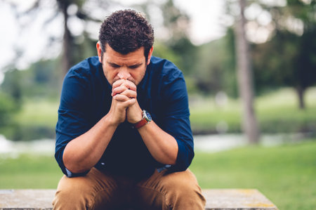 A closeup of a man sitting on a bench in a parkの写真素材