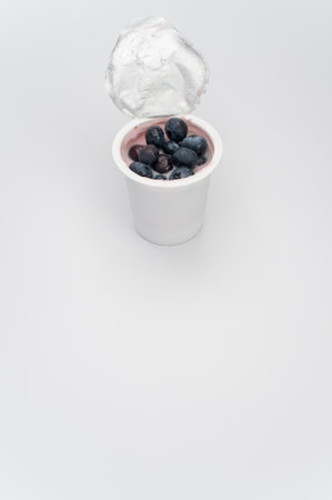 A vertical shot of a cup of yogurt with fresh berries on a white surfaceの写真素材