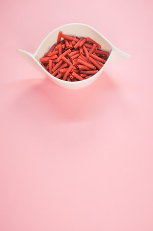A bowl of dry macaroni pasta isolated on a pink background with free space for textの写真素材