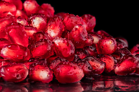 A Close-up of pomegranate seeds with water drops reflecting onto a black backgroundの写真素材