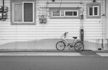 A greyscale shot of a bicycle in front of an old wooden house captured in South Koreaの写真素材