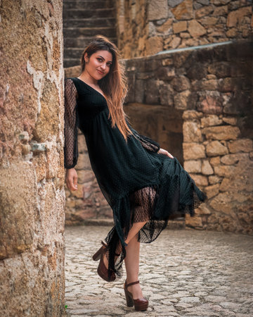 A female model in a black long dress posing near a buildingの写真素材